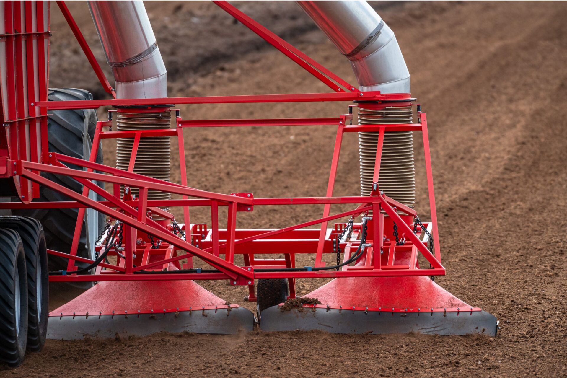 Close-up of red machinery used for peat extraction in a field, showcasing ETEPEK's advanced technology for sustainable peat harvesting.