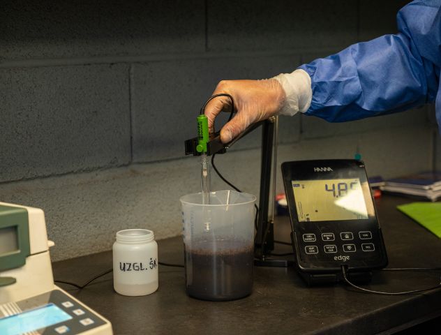 Laboratory testing of peat moss by ETEPEK, showing a technician measuring pH levels with precision equipment.