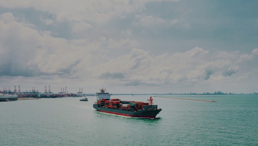 Cargo ship approaching port with containers, symbolizing global shipping and logistics